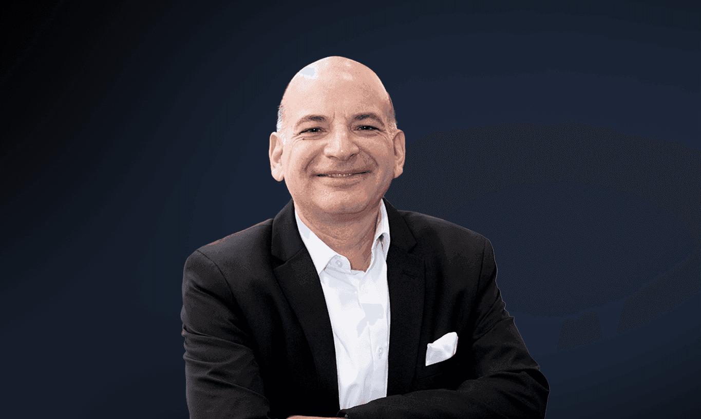 Smiling bald man in a black suit and white shirt, looking directly at the viewer.